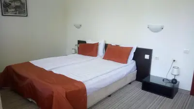 a bedroom with a large bed with orange pillows at Spa Hotel Planinata in Ribarica