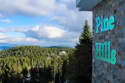 a sign on the side of a building with a mountain at Aparthotel Pine Hills Pamporovo in Pamporovo