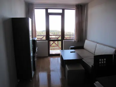 a living room with a couch and a large window at Aparthotel Pine Hills Pamporovo in Pamporovo
