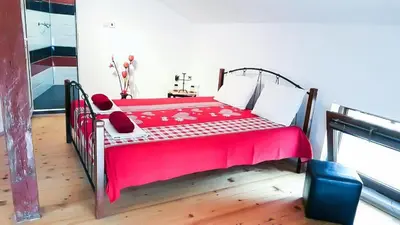 a bedroom with a red bed with a red blanket at The Old House guest rooms and apartament in Plovdiv