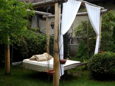 a bed in a garden with a swing at The Gates Apartments in Koprivshtitsa