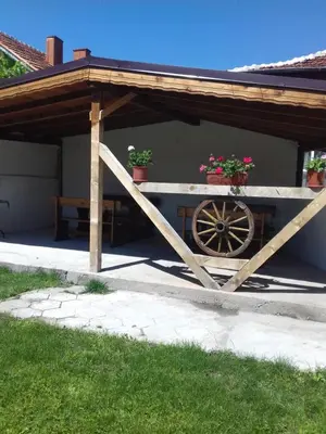 a woodenilion with a wooden wheel in front of a house at Къща Момина сълза in Sapareva Banya