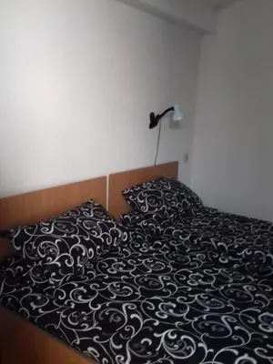 a bed with a black and white blanket and a lamp at Къща Момина сълза in Sapareva Banya