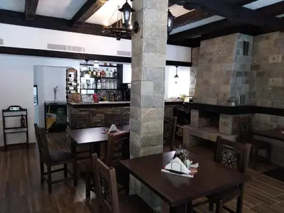a restaurant with wooden tables and chairs and a bar at Complex Magic of the Rhodopes in Bachkovo