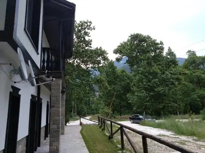 a building with a fence and a car on a road at Complex Magic of the Rhodopes in Bachkovo