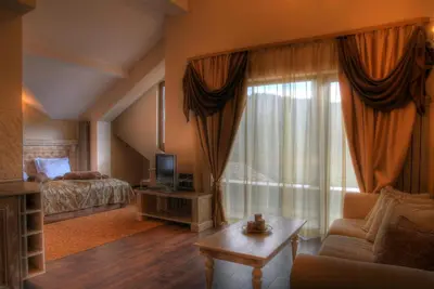 a hotel room with a bed and a television and a living room at Hotel Iva & Elena in Pamporovo