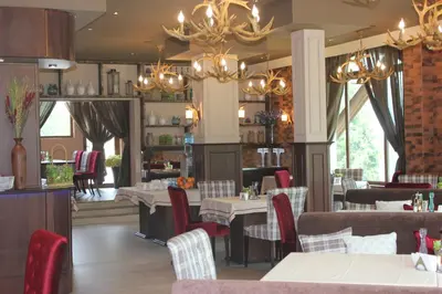 a dining room with tables and chairs and chandeliers at Hotel Iva & Elena in Pamporovo