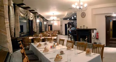 a dining room with tables and chairs and a fireplace at Hotel Iva & Elena in Pamporovo