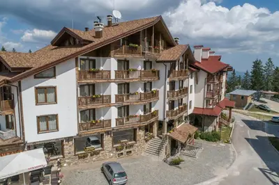 an apartment building with balconies and a parking lot at Hotel Iva & Elena in Pamporovo