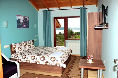 a bedroom with a bed and a large window at Къщи за гости Илиеви , Цигов Чарк in Batak
