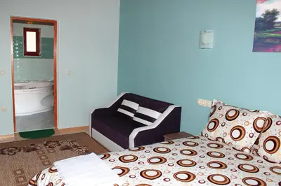 a bedroom with a bed and a chair and a mirror at Къщи за гости Илиеви , Цигов Чарк in Batak