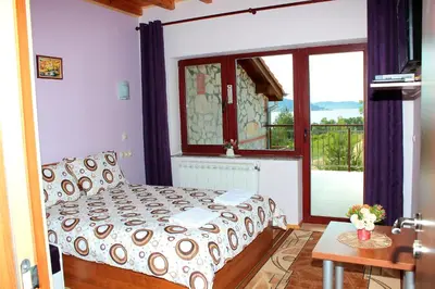 a bedroom with a bed and a large window at Къщи за гости Илиеви , Цигов Чарк in Batak