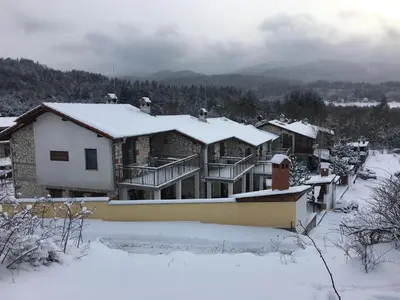 a house with snow on the roof of it at Къщи за гости Илиеви , Цигов Чарк in Batak