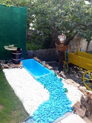 a backyard pool with blue rocks and a tree at Guest Rooms IDeR in Sapareva Banya