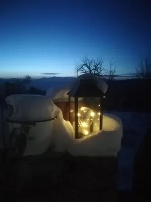 a lantern with lights in the snow at night at Скендерова Къща Къщичка Алиса in Leshten