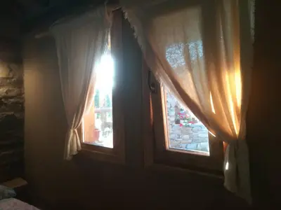 a room with a window with a curtain and a light at Скендерова Къща Къщичка Алиса in Leshten