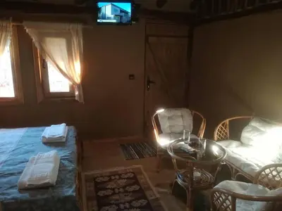 a living room with a bed and a table and chairs at Скендерова Къща Къщичка Алиса in Leshten