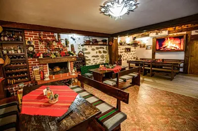 a room with tables and a fireplace in a restaurant at Къща за гости Плевнята in Bansko