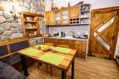 a kitchen with a wooden table and a barn door at Къща за гости Плевнята in Bansko