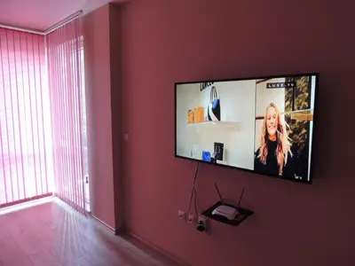 a flat screen tv hanging on a wall in a room at Хисаря ВИП апартаменти in Hisarya