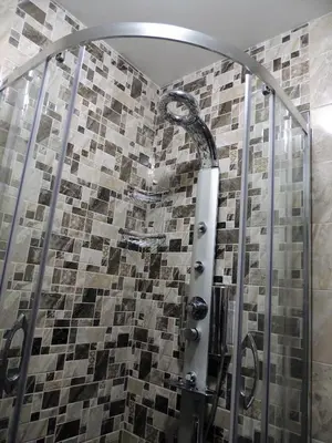 a shower with a mosaic tile wall in a bathroom at Хисаря ВИП апартаменти in Hisarya