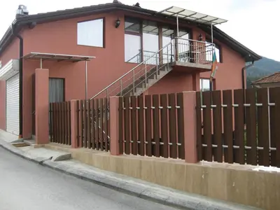 a red house with a fence in front of it at Къща за гости Романс in Yagodina