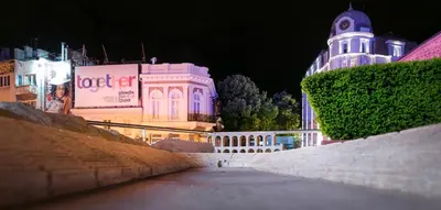 a lit up building with a clock tower at night at Shahbazian House in Plovdiv