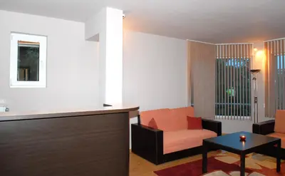 a living room with an orange chair and a table at Hotel Avis in Sandanski