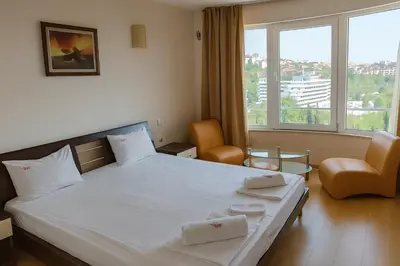 a bedroom with a large white bed and two chairs at Hotel Avis in Sandanski