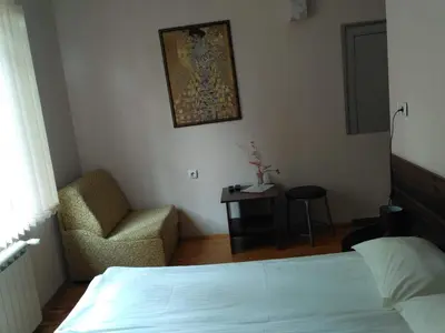 a bedroom with a bed and a chair and a table at семеен хотел 