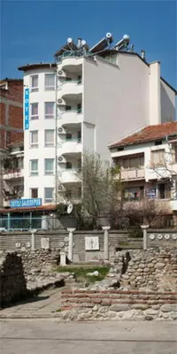 a tall white building in front of a building at Hotel Balevurov in Sandanski