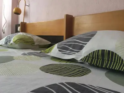 a bed with a wooden headboard and pillows on it at Hotel Balevurov in Sandanski