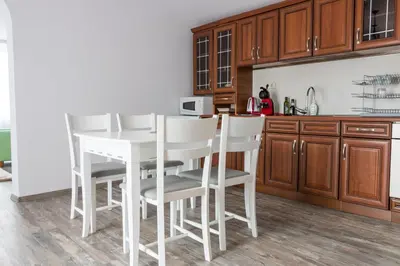 a kitchen with wooden cabinets and a white table and chairs at Apartments Nasini by Flat Mаnager in Plovdiv