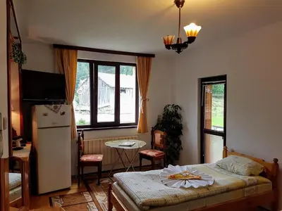 a bedroom with a bed and a table and a refrigerator at Къща за гости 