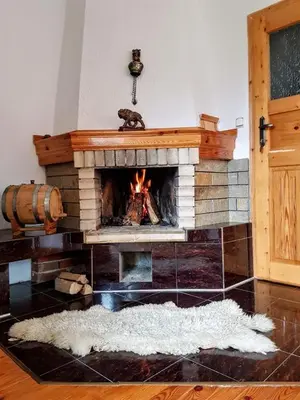 a fireplace in a living room with a fire at Къща за гости 