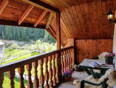 a balcony of a cabin with a table and a window at Къща за гости 