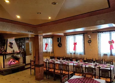 a banquet hall with tables and chairs and a fireplace at Къща за гости 