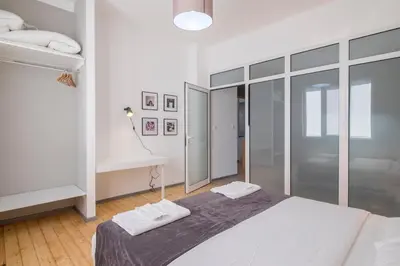 a white bedroom with a bed and a desk at blueWaveplace - Stylish 2 BR Home in Center of Sofia in Sofia