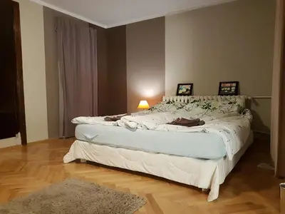 a bedroom with a large bed with a lamp and a rug at Artistic studio in Sofia's top center in Sofia