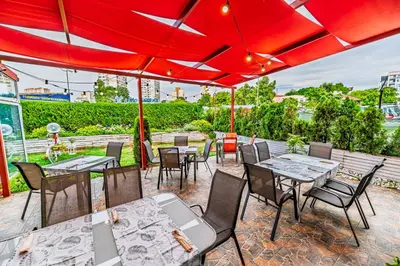 a patio with tables and chairs under a red umbrella at Art Hotel Simona in Sofia