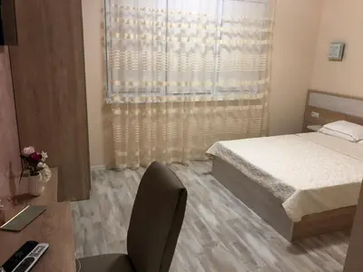 a bedroom with a bed and a desk and a window at ФЛАМА РЕЗИДЕНТС in Plovdiv