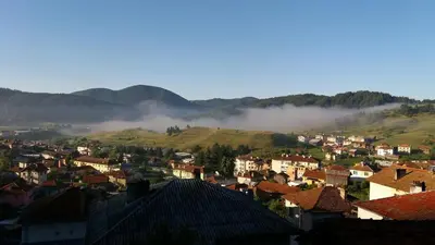 a small town in a valley with fog in the mountains at Къща за гости МЕЛИСА in Borino