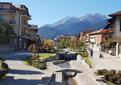 a person walking down a street with mountains in the background at Family 2 bed Apartment in Bansko in Bansko
