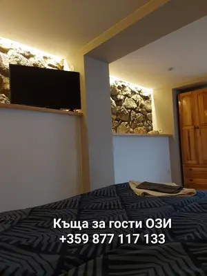 a bedroom with a bed and a tv on a wall at Къща за гости Ози in Ovchartsi