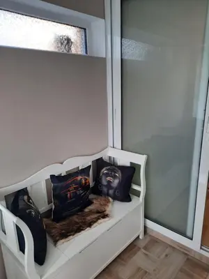 a white bench with pillows on it next to a window at Къща за гости Ози in Ovchartsi