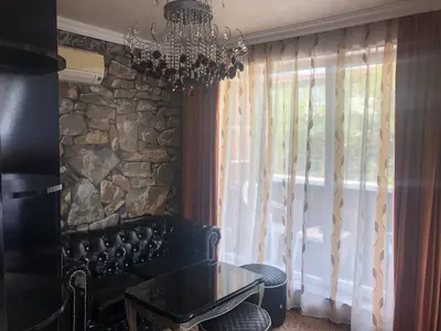 a dining room with a chandelier and a stone wall at Стаи за гости Топ Старс Смолян in Smolyan
