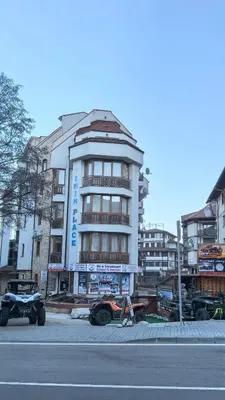a building with cars parked in front of a street at Nice and quiet apartment next to Gondola lift. in Bansko