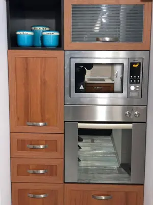 a microwave oven sitting inside of a wooden cabinet at Cosy House in Sofia