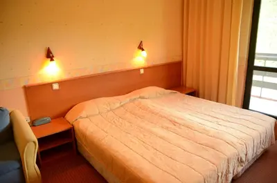 a bedroom with a bed and a desk with lights at Park Hotel Ribaritsa in Ribarica