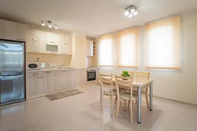 a kitchen with a table and chairs and a refrigerator at Апартамент АВА in Sandanski